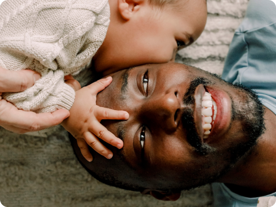 A father and his baby lying on the floor.