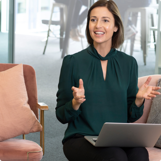 A young woman in a green shirt working in a lounge on her laptop