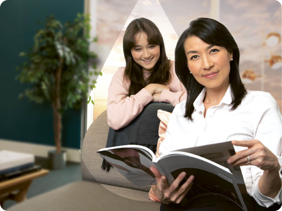 A woman reading a magazine with her daughter.