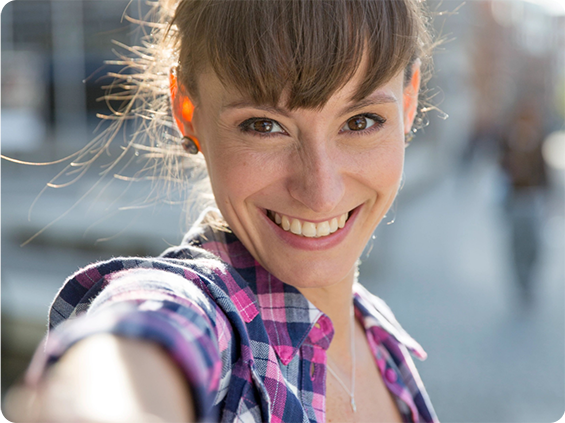 A woman smiling taking a selfie in the afternoon sun