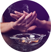 Two hands held over an ashtray blocking the smoke from rising
