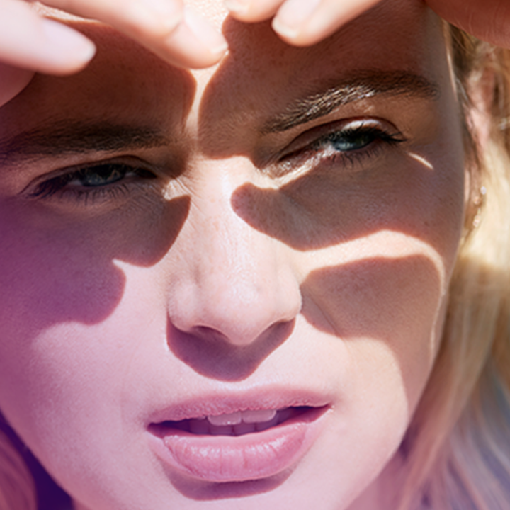 Woman suffering from dry eyes, shielding her eyes and squinting into the sun
