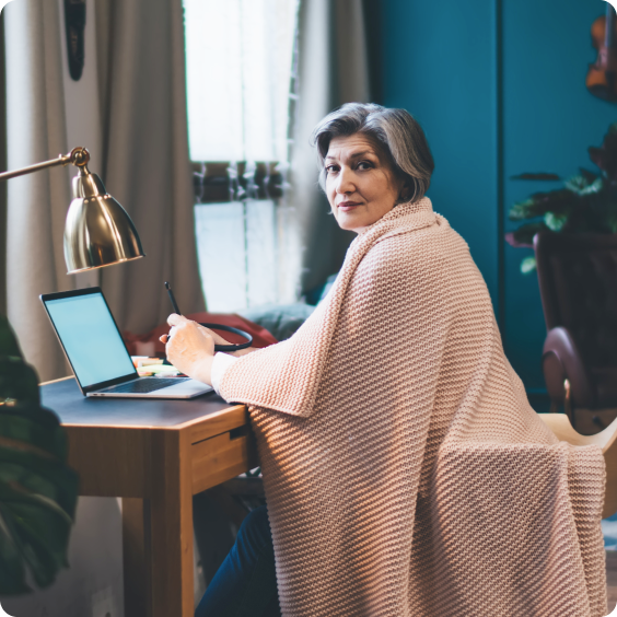 Femme âgée assise à un bureau avec un ordinateur portable.