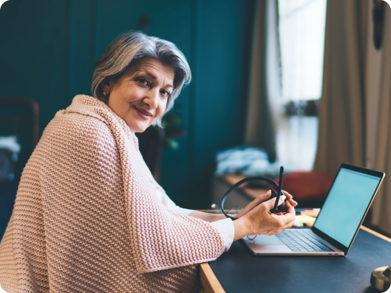 Femme âgée assise à un bureau avec un ordinateur portable.
