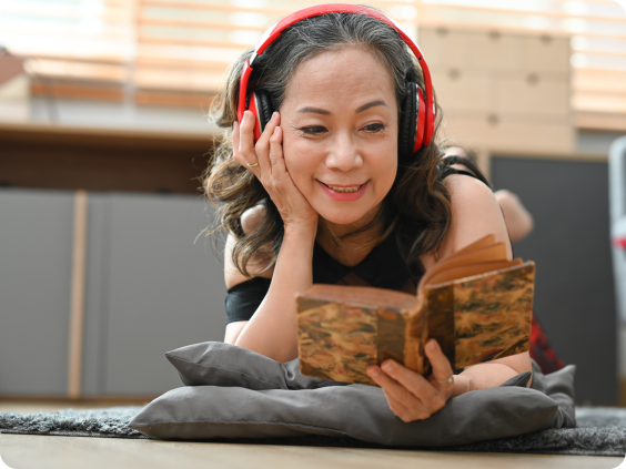 Femme âgée avec des écouteurs lisant un livre