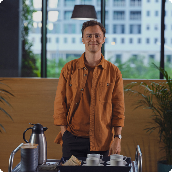 A smiling man wearing a brown shirt.