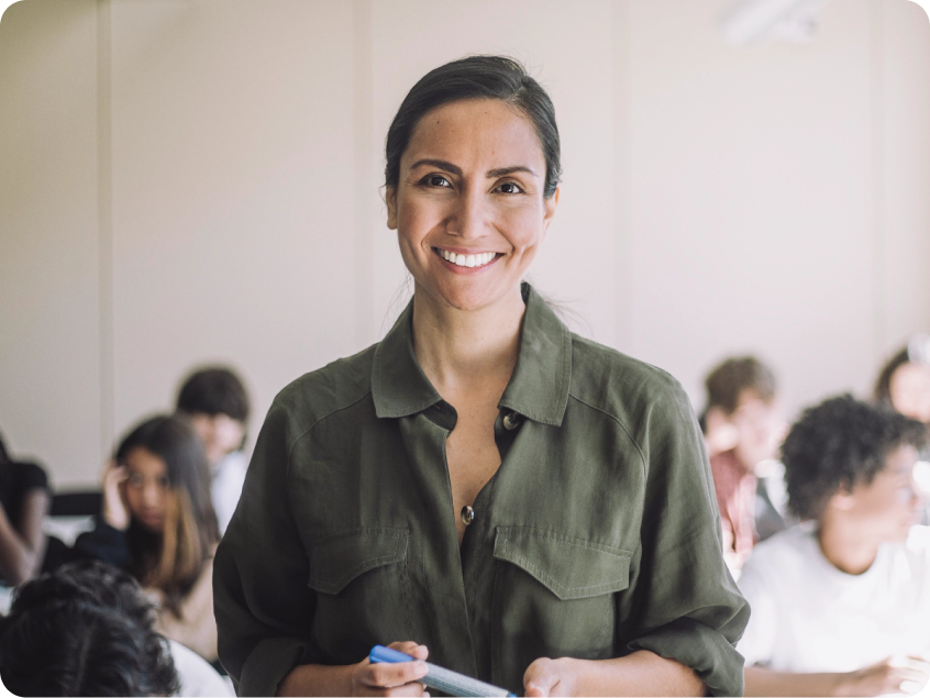 Smiling woman in a green shirt with a classroom in the background