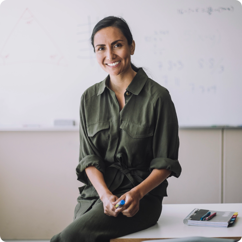 Smiling woman in a green shirt with a blackboard in the background